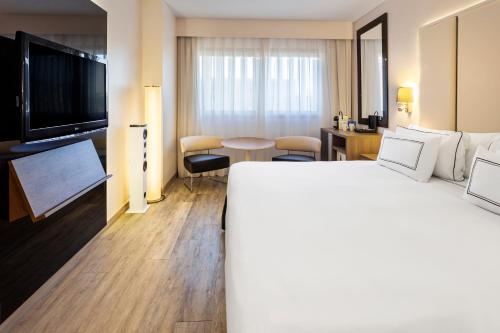 a hotel room with a large bed and a flat screen tv at Melia Lebreros in Seville