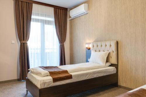 a hotel room with a bed and a window at Family Hotel LILIUM in Kirkovo