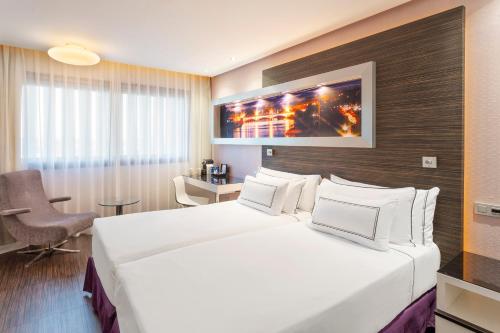 a hotel room with a large white bed and a chair at Melia Lebreros in Seville