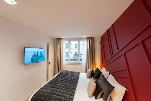 une chambre d'hôtel avec un lit avec une tête de lit rouge dans l'établissement Bistrot, à Paris