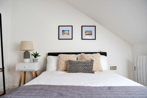 a white bedroom with a large bed with pillows at Finest Retreats - Tolcarne Stay - Luxury Newquay Apartment in Newquay