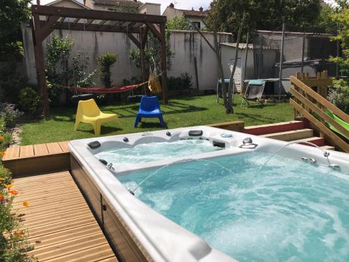 a hot tub in a backyard with two chairs at Espace Beléverte Bussière 1 Tamaris appartement meublé de 2 chambres in Oullins