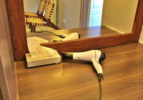 a hair dryer sitting on the floor in front of a mirror at Tlou Safari Lodge in Kasane