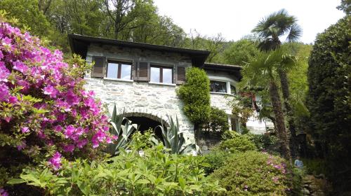 a stone house with flowers in front of it at Casa Ilvea in Cavigliano