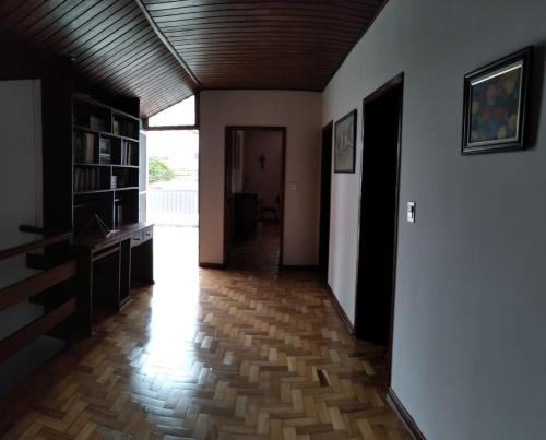 um corredor com um quarto com piso em madeira em Casa residencial no centro de Guaratinguetá em Guaratinguetá