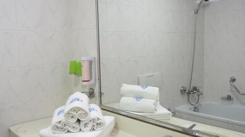 a bathroom with a mirror and a pile of towels at Hotel Tennis Club in Prostějov