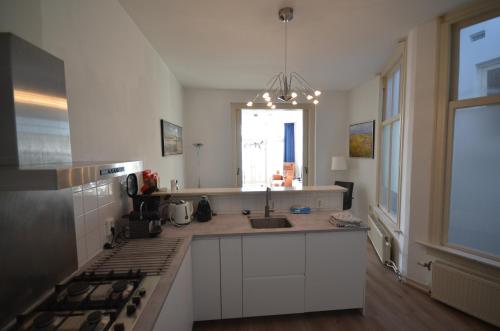 a kitchen with white cabinets and a sink and a window at Fraai appartement direct aan zee op toplocatie. in Vlissingen