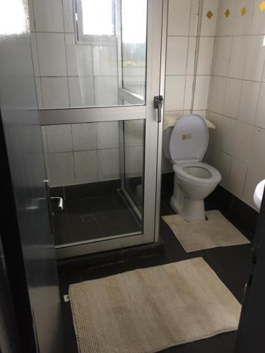 a bathroom with a shower and a toilet with rugs at ABT Apartments Bonapriso-7Mins From Airport in Douala