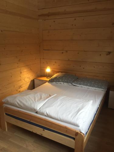 a bed in a wooden cabin with a light on it at Dom z bala Dar Lasu in Szczytno