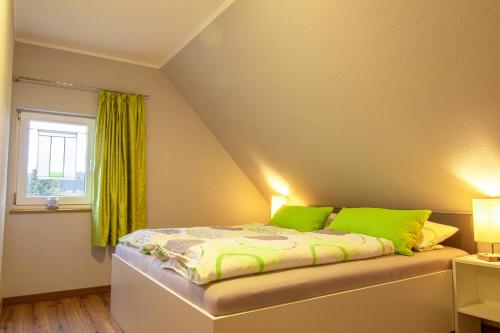 Un dormitorio con una cama con almohadas verdes y una ventana en Pension & FeWo's Talblick, en Weitersglashütte