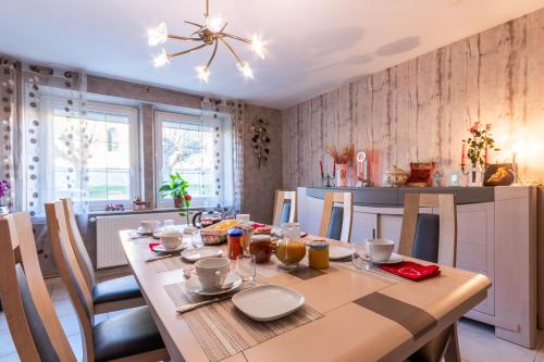 ein Esszimmer mit einem Holztisch und einer Küche in der Unterkunft Flopre chambre d'hote in Flocourt