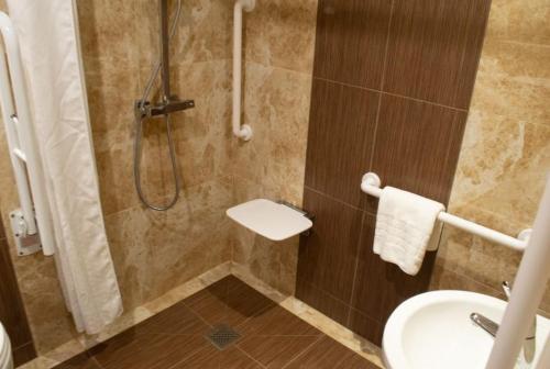 a bathroom with a shower with a sink and a toilet at Tong Park Hotel in Bradford