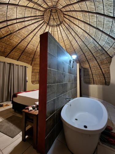 a bathroom with a tub in a room with a bed at Mountain Aloe Den in Barberton