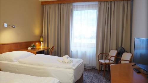 a hotel room with two beds and a television at Hotel Tennis Club in Prostějov