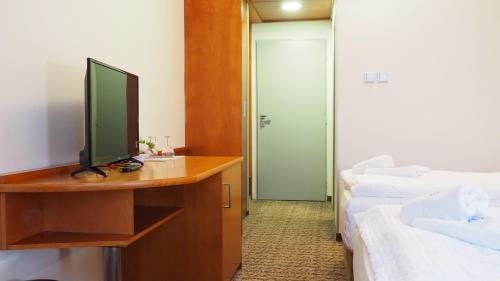 a room with a television on a desk with two beds at Hotel Tennis Club in Prostějov