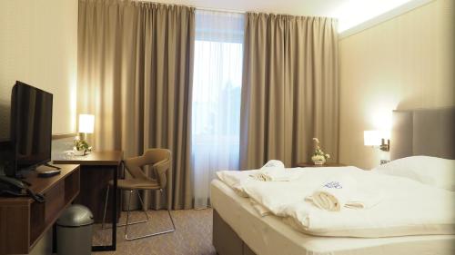 a hotel room with a bed and a desk and a television at Hotel Tennis Club in Prostějov