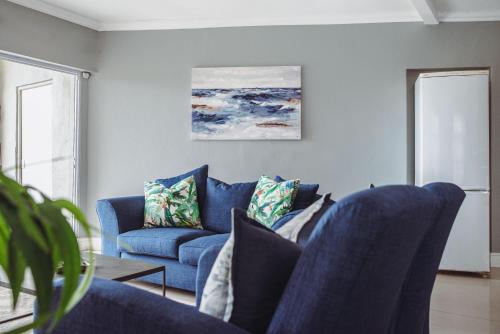 a living room with blue chairs and a blue couch at Harbour Cottages, Humewood in Port Elizabeth
