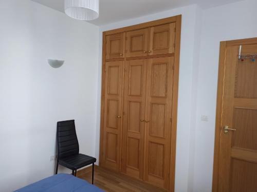 a bedroom with a wooden closet and a black chair at Sierra y Silencio Nómada, WIFI, Trastero y Garaje in Güéjar-Sierra