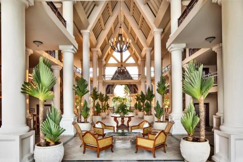 a lobby with chairs and a table and palm trees at The Residence Mauritius in Belle Mare