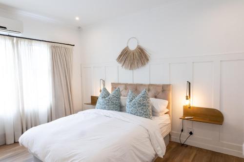 a bedroom with a large white bed with blue pillows at Peaceful Modern Home with Private Garden in Durban North in Durban