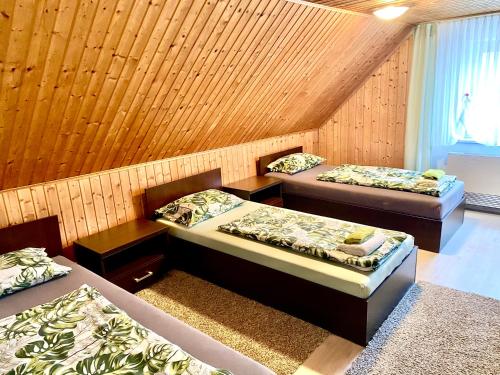 3 Betten in einem Zimmer mit Holzwänden in der Unterkunft RIEDWIRTSHAUS in Neu Ulm