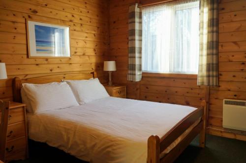 1 dormitorio con 1 cama en una cabaña de madera en Woodland Pine Lodge en Killin