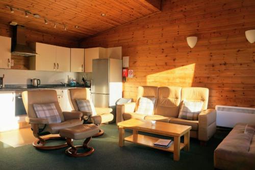 a living room filled with furniture and a kitchen at Woodland Pine Lodge in Killin