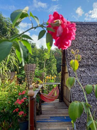a garden with a wooden walkway with a red flower at Tribal Village Homestay & Trekking in Banlung