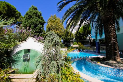 einen Pool mit einem Leguan-Haus und Palmen in der Unterkunft Homiday - Holiday Rendez Vous in Pineto