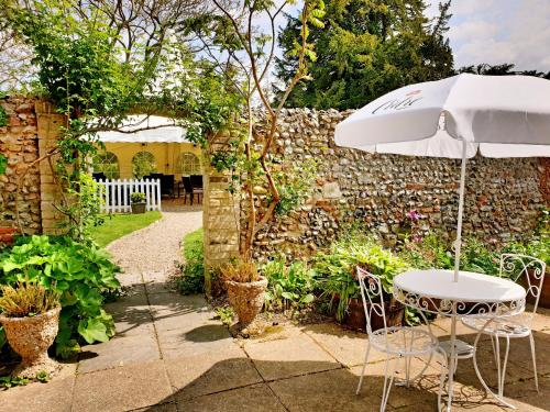 una mesa y una sombrilla en un jardín en The Crown House Inn en Great Chesterford
