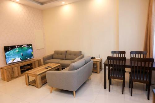 a living room with a couch and a tv and chairs at The M Suite in Juffair
