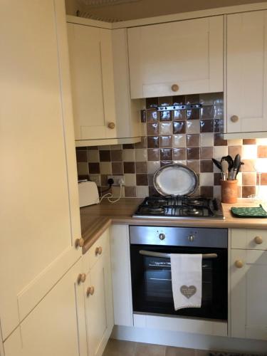 a kitchen with white cabinets and a stove top oven at Beautiful riverfront cosy one bedroom apartment in Upton upon Severn