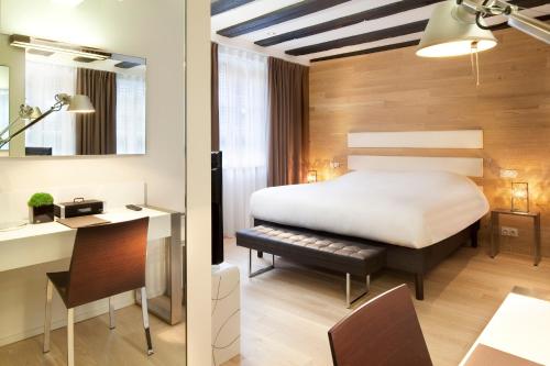 a hotel room with a bed and a desk and a desk at Hotel Le Colombier Suites in Colmar