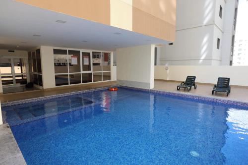 a large swimming pool with two chairs in a building at The M Suite in Juffair