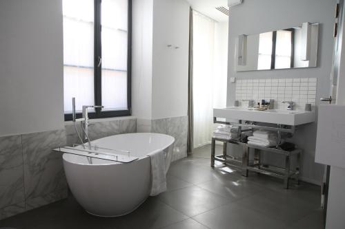 Baño blanco con bañera y lavamanos en Hôtel Quatorze en Colmar