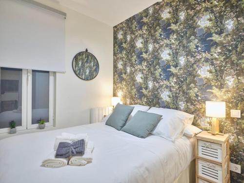1 dormitorio con 1 cama blanca grande y papel pintado con motivos florales en NEW Retiro recién reformado 10 min en metro a Sol, hasta seis personas, en Madrid