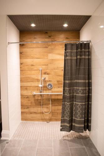 a bathroom with a shower with a wooden wall at Colonial Hotel & Suites in Grand Bend
