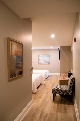 a room with a bed and a chair and a table at Colonial Hotel & Suites in Grand Bend