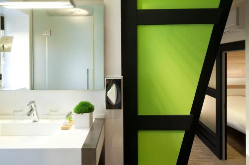 a bathroom with a green wall next to a sink at Hotel Le Colombier Suites in Colmar