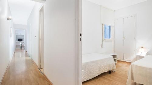 a white bedroom with two beds and a mirror at 1 Mars 1 - Llafranc in Llafranc