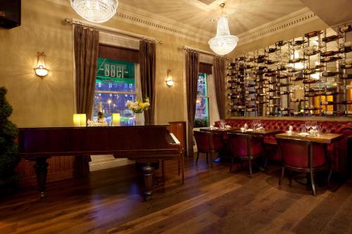 a restaurant with a piano in a room with a bar at Harcourt Hotel in Dublin