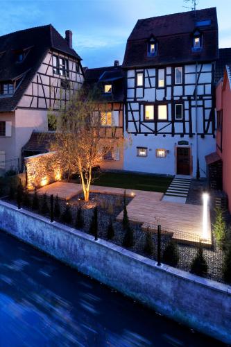 a house next to a river with a building at Hotel Le Colombier Suites in Colmar