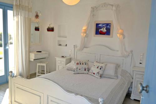 a white bedroom with a white canopy bed with pillows at Annio studios in Plaka