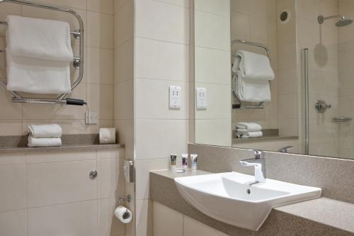 a white bathroom with a sink and a mirror at Sunday Box Hill Burford Bridge Hotel in Dorking