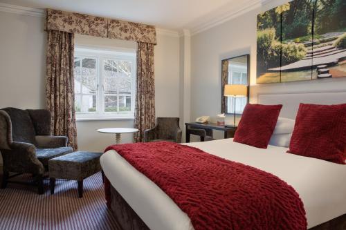 a bedroom with a bed and a chair and a window at Sunday Box Hill Burford Bridge Hotel in Dorking
