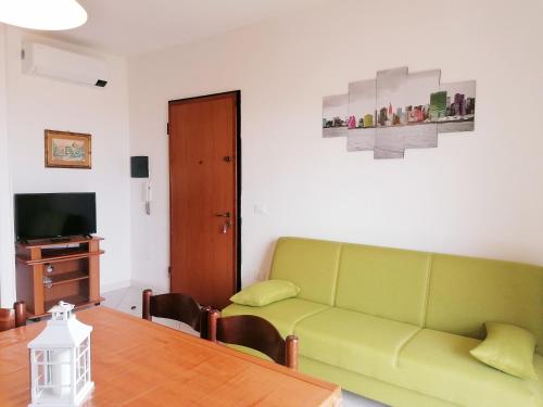 salon z zieloną kanapą i stołem w obiekcie Appartamenti OIKOS con Vista Mare e Wi-Fi w mieście Castelsardo