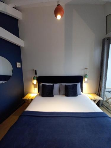 a bedroom with a large bed with blue sheets and pillows at Hôtel La Caravelle in Ciboure
