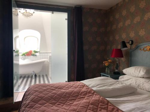 a bedroom with a bed and a bathroom with a tub at Hotel Kung Carl, WorldHotels Crafted in Stockholm