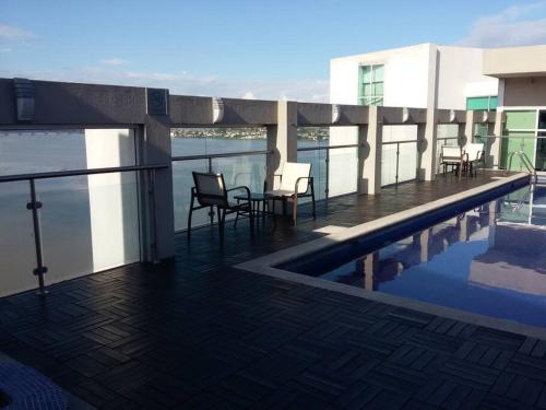 a balcony with a table and chairs next to a swimming pool at Ecusuites Jacuzzi Executive Dpto Riverfront l puerto santa ana in Guayaquil