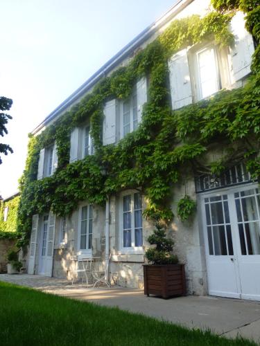 an ivy covered building with white doors and windows at Hôtel La Tonnellerie in Beaugency